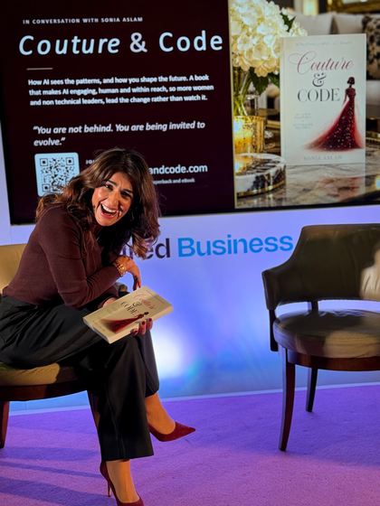 Sonia Aslam laughing on stage with her book